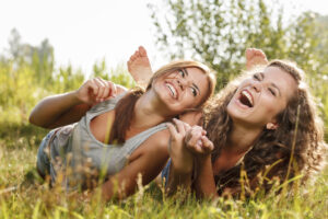 Two girl friends laughing in the grass