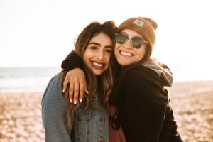 Two girl friends smiling with each other at the beach