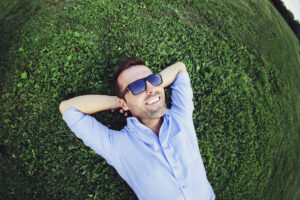 Guy laying in the green grass and smiling