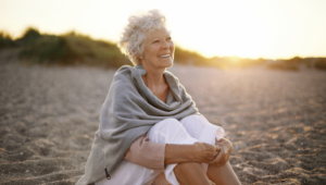 Older woman sitting on the beach during sunset