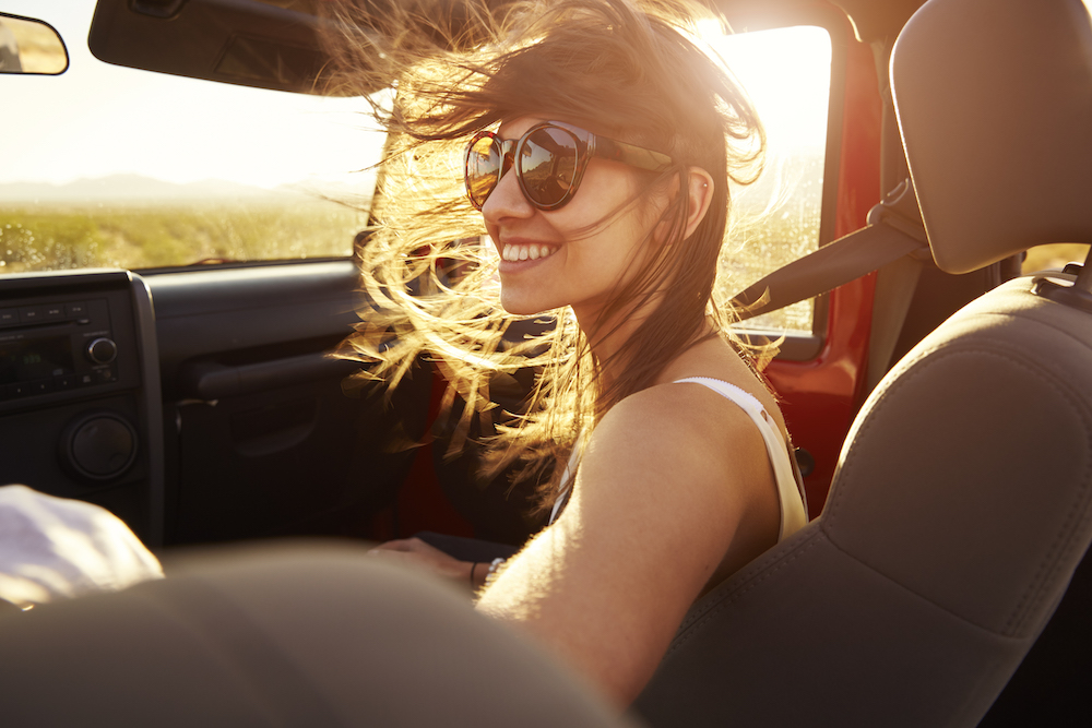 Woman having a good time and smiling in the passenger seat of a jeep