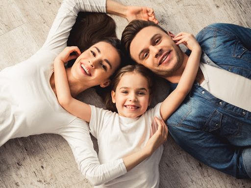 family of three smiling from the floor