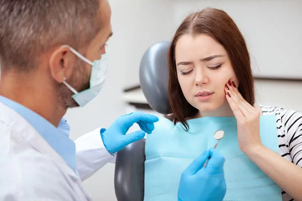 young lady at the dentist holding her cheek